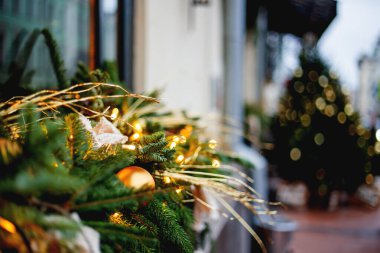 Noel ve Yeni Yıl dış dekorasyonları - geleneksel köknar ağacı çelenkleri ampuller, çam kozalakları ve toplarla.