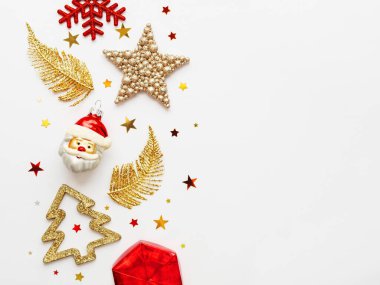 Kırmızı ve altın yeni yıl süslemeleri. Parlak parlak tüyler ya da yapraklar, köknar ağacı, Noel Baba ve Noel ağacı için yıldız konfetileri. Üst manzara, düz uzanma.