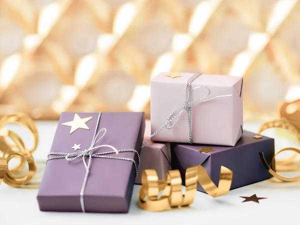 Regalos navideños. Regalos envueltos en papel rosa pálido y violeta con cintas de plata. Arcos dorados brillantes . —  Fotos de Stock