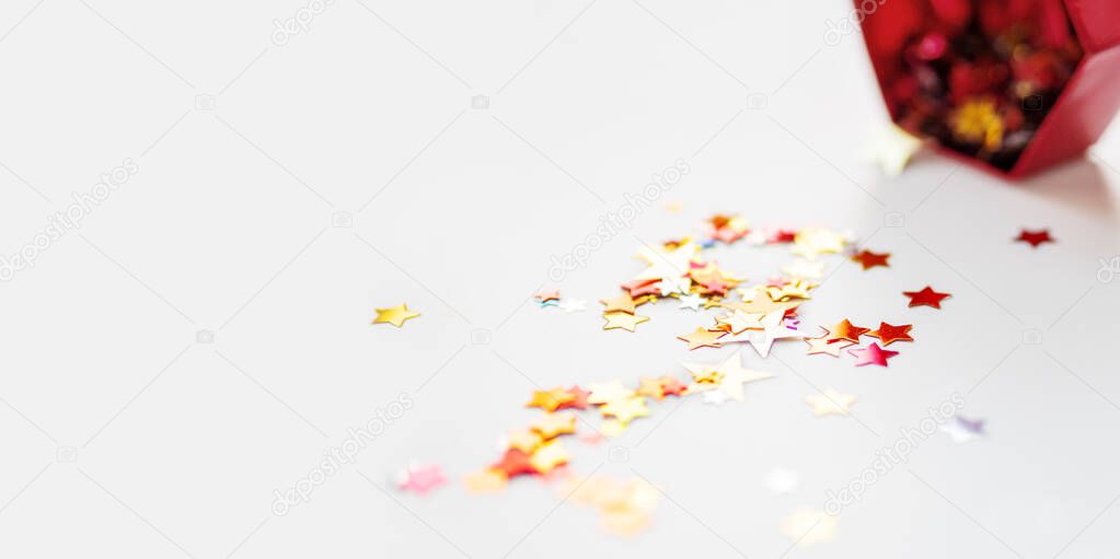 Banner with stars confetti which fallen from red sparkling box. Holiday decoration on white background.