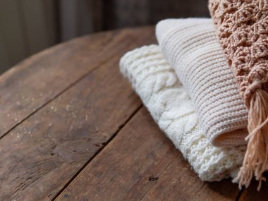 Beyaz, bej ve kahverengi eski ahşap arka planda örülmüş süveterler..