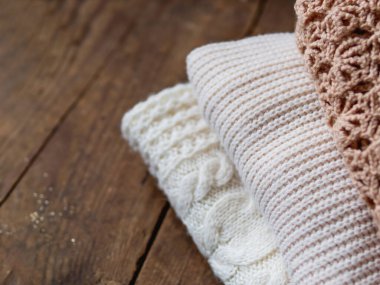 Beyaz, bej ve kahverengi eski ahşap arka planda örülmüş süveterler..