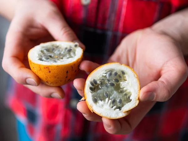 Homem de camisa xadrez tartan detém Passiflora ligularis, vulgarmente conhecido como o granadilla doce ou grenadia, também conhecido como mangostão roxo. Colheita de frutas exóticas . — Fotografia de Stock