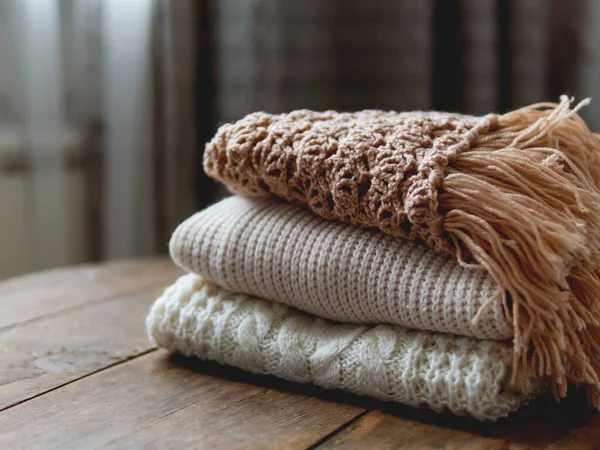 Белые, бежевые и коричневые вязаные свитера на потрепанном деревянном фоне . — стоковое фото