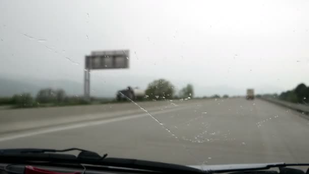 Een roadtrip bij slecht weer. De ruitenwissers verwijderen regendruppels uit de voorruit van de auto. — Stockvideo