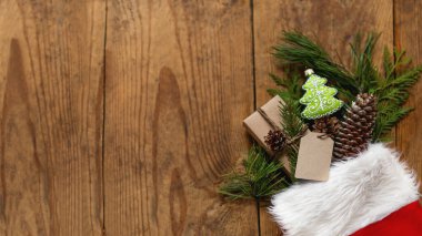 Noel Baba 'nın kırmızı çorabına doğal köknar ağacı ve süs olarak da thuja dalları sarılmış Noel hediyeleri. En iyi manzara, tahta masaya uzanmış yeni yıl hediyeleri..