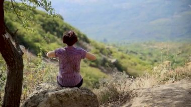 Hayalet Vadisi 'nde taş üstünde oturan genç bir kadın. Güzel yaz manzarası. Demerdgi Dağları, Kırım.