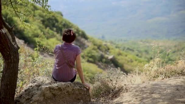 La giovane donna e 'seduta sulla pietra nella Valle dei Fantasmi. Bellissimo paesaggio estivo. Demerdgi monti, Crimea . — Video Stock