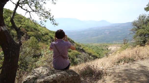 Young woman is sitting on stone in Ghost Valley. Beautiful summer landscape. Demerdgi mountains, Crimea. — Stock Video