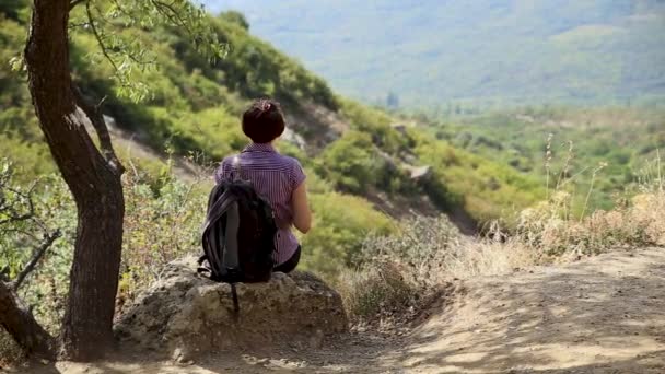 Νεαρή γυναίκα κάθεται πάνω σε πέτρα στο Ghost Valley. Όμορφο καλοκαιρινό τοπίο. Βουνά Demerdgi, Κριμαία. — Αρχείο Βίντεο