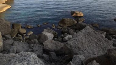 Deniz sörfü. Novy Svet köyündeki Golitsyn yolu yakınlarındaki kayalık sahilde sakin dalgalar esiyor. Kırım.