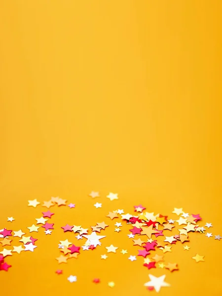 Fondo amarillo de vacaciones con colorido confeti estrella. Buen fondo para las tarjetas de Navidad y Año Nuevo . —  Fotos de Stock