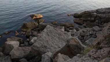 Deniz sörfü. Novy Svet köyündeki Golitsyn yolu yakınlarındaki kayalık sahilde sakin dalgalar esiyor. Kırım.