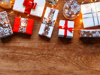 Eski ahşap arka planda Noel hediyeleri. Beyaz ve altın renkli, kurdeleli ve ampullü hediyeler. Üst görünüm, düz görünüm, kopyalama alanı.