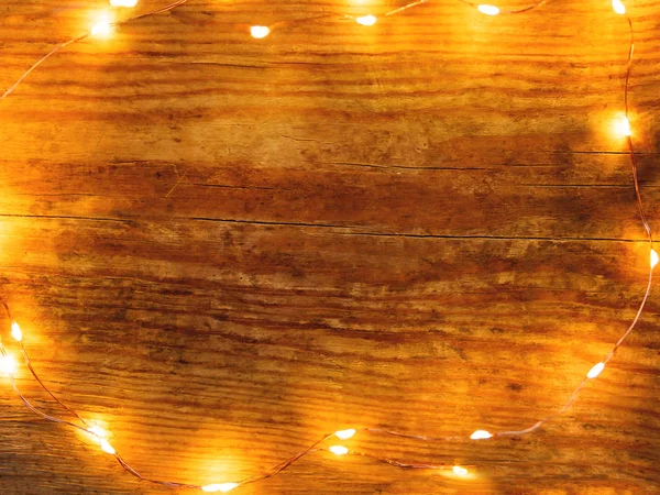 Feestelijke armoedige houten ondergrond met gloeilampen. Bovenaanzicht, vlak lay. — Stockfoto