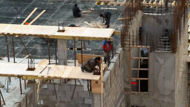 Odintsovo, Rusland - 02 december 2015. Timelapse clip van de bouw. Arbeiders in oranje uniform bouwen een flatgebouw onder de regen. — Stockvideo