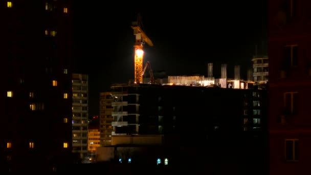 ODINTSOVO, RUSSIA - October 20, 2015. Timelapse clip of building construction at night. Workers in orange uniform build an apartment building. Construction crane moves from one side to another. — Stock Video