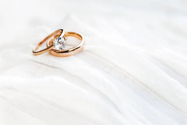 Golden wedding rings with diamond on white fabric. Symbol of love and marriage. — Stock Photo, Image