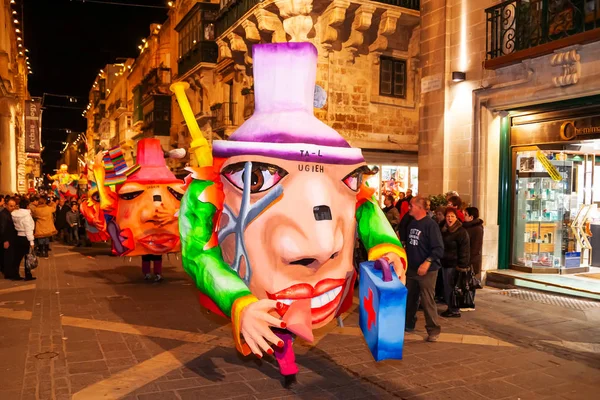 VALLETTA, MALTA - 13 de febrero de 2010. Fiesta nocturna tradicional. Carnaval con muñecas gigantes en movimiento y gente en trajes coloridos . — Foto de Stock