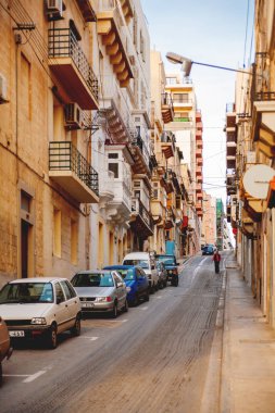 Valletta, Malta - 13 Şubat 2010. Adam dar bir sokakta yürüyor. Balkonlu eski binalar.