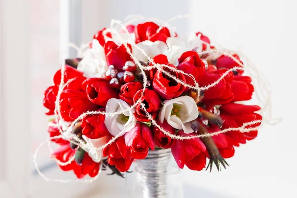 Ramo de novia en jarrón de vidrio a la luz del sol. Composición floral tradicional con tulipanes rojos brillantes en el alféizar de la ventana . — Foto de Stock