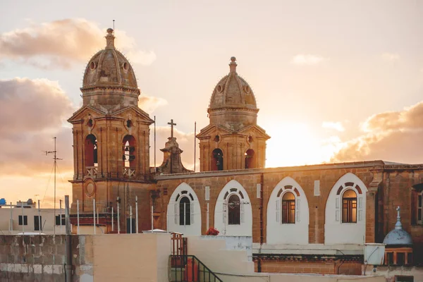 Puesta de sol detrás de los campanarios de la iglesia parroquial Nuestra Señora del Monte Carmelo. Gzira, Malta — Foto de Stock