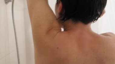 Woman shaves her armpits with a razor. Slow motion video in bathroom. Close up video of wet skin.