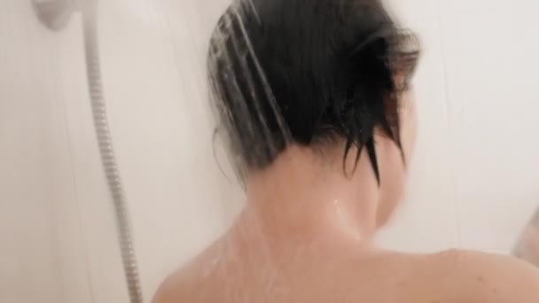 Nackte Frau nimmt eine Dusche. Frau wäscht ihre kurzen Haare mit Shampoo. Zeitlupenvideo im weißen Badezimmer. — Stockvideo