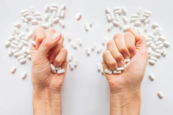 Palm hands full of white scattering pills. Woman gripes hand with capsules with medicines on light background. Flat lay, top view.