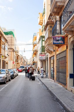 SLIEMA, MALTA - 12 Şubat 2010. Bavullu turistler sokakta yürüyorlar..