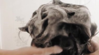 Naked woman takes a shower. Woman washes her short hair with shampoo. Slow motion video in white bathroom.