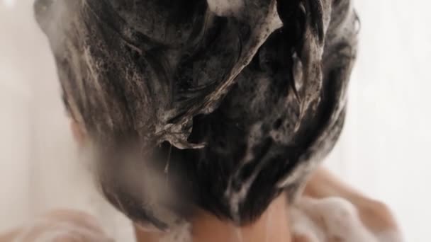 Naakte vrouw neemt een douche. Vrouw wast haar korte haar met shampoo. Slow motion video in witte badkamer. — Stockvideo