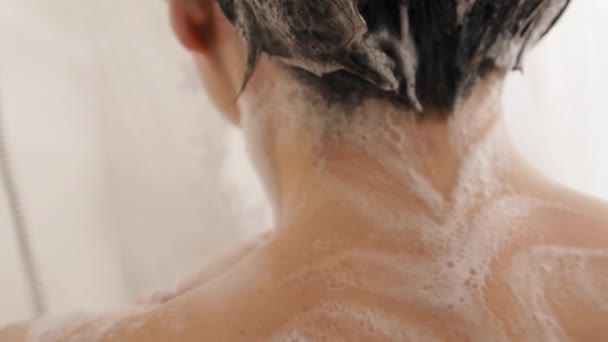 Naakte vrouw neemt een douche. Vrouw wast haar korte haar met shampoo. Slow motion video in witte badkamer. — Stockvideo