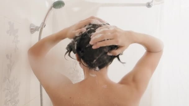 Una mujer desnuda toma una ducha. La mujer se lava el pelo corto con champú. Vídeo en cámara lenta en baño blanco . — Vídeos de Stock