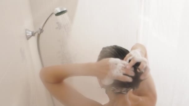 Naakte vrouw neemt een douche. Vrouw wast haar korte haar met shampoo. Slow motion video in witte badkamer. — Stockvideo