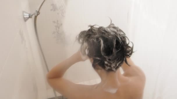 Una donna nuda si fa una doccia. Donna lava i capelli corti con lo shampoo. Video al rallentatore in bagno bianco . — Video Stock