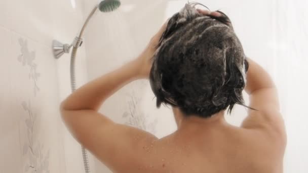 Una donna nuda si fa una doccia. Donna lava i capelli corti con lo shampoo. Video al rallentatore in bagno bianco . — Video Stock