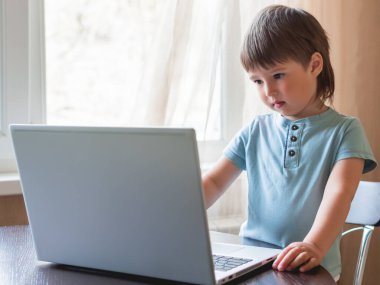 Meraklı çocuk dizüstü bilgisayarı keşfediyor ve klavyedeki tuşlara basıyor..