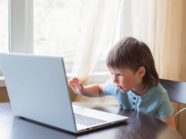 Meraklı çocuk dizüstü bilgisayarı keşfediyor ve klavyedeki tuşlara basıyor..
