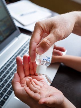 Koronavirüs salgını yüzünden kendini soyutlama. Deri sterilizasyonu için tıbbi dezenfekte jeli kullanan bir adam. Babası küçük oğluyla uzaktan çalışıyor..