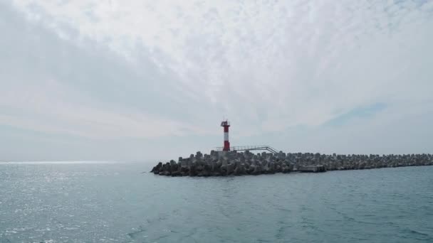 Vista de la casa de luz roja y blanca a rayas desde el barco en movimiento. Paisaje marino con buen tiempo . — Vídeo de stock