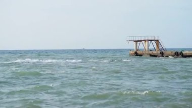 Deniz manzaralı güzel bir hava. Sahilden eski paslı iskelenin manzarası. Soçi, Rusya.