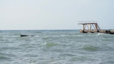 Deniz manzaralı güzel bir hava. Sahilden eski paslı iskelenin manzarası. Soçi, Rusya.