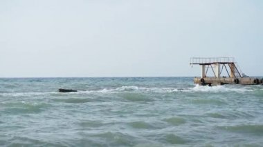 Deniz manzaralı güzel bir hava. Sahilden eski paslı iskelenin manzarası. Soçi, Rusya.