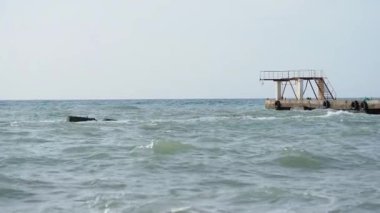 Deniz manzaralı güzel bir hava. Sahilden eski paslı iskelenin manzarası. Soçi, Rusya.