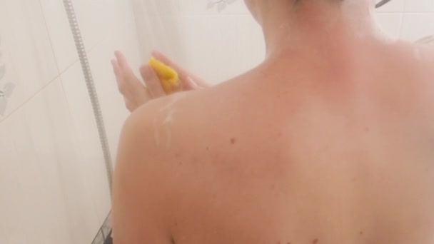 Donna nuda con i capelli corti si fa una doccia con divertente anatra di gomma gialla. La donna si lava le spalle con una spugna gialla. Bagno bianco . — Video Stock