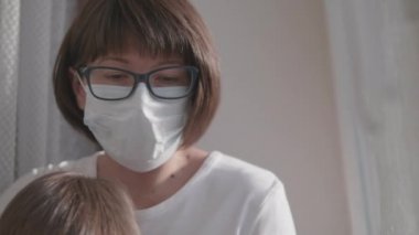 Kadın uzaktan kumandası evden çalışıyor. Dizüstü bilgisayarı ve dizlerinin üstünde tatlı bir bebekle pencere pervazında oturuyor. Coronavirüs COVID19 yüzünden karantina altına alındı. Evde kendini izole et. 10bit V günlük kaydı