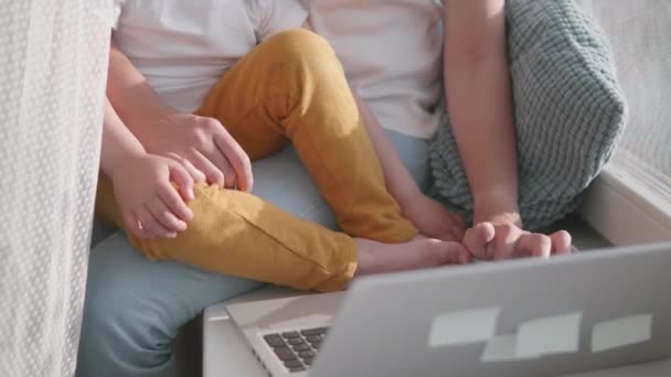 Afgelegen vrouw werkt vanuit huis. Ze zit op de vensterbank met laptop en knappe peuter op haar knieën. Afsluiting quarantaine vanwege het coronavirus COVID19. Zelfisolatie thuis. 10bit V-logL — Stockvideo