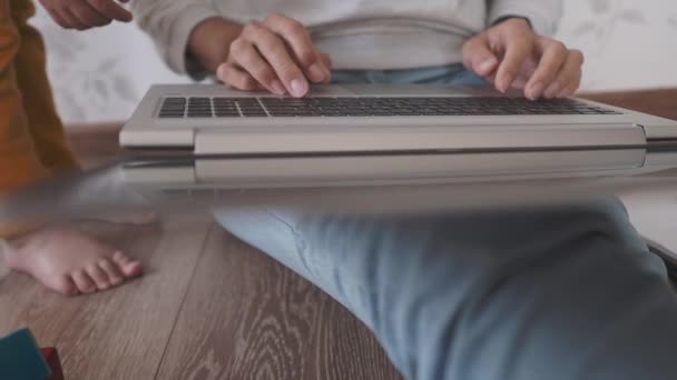 Mam en zoon zitten thuis in quarantaine vanwege het coronavirus COVID19. Moeder werkt op afstand met laptop, zoon speelt met speelgoed blokken. Zelfisolatie thuis. — Stockvideo