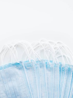 Mavi koruyucu tıbbi maske sürüsünün üst görüntüsü. Coronavirus COVID-19 konsepti beyaz arkaplan ve kopyalama alanı.